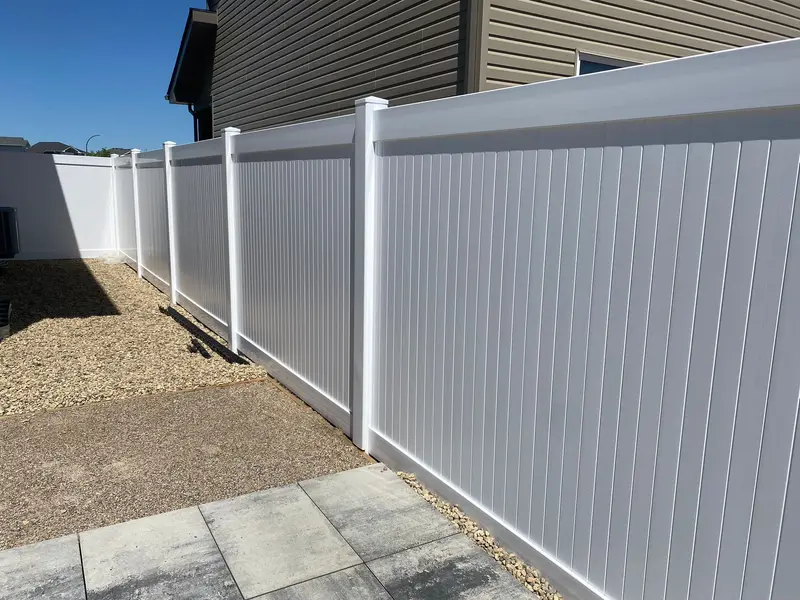White Vinyl Privacy Fence White vinyl privacy fence with flat-cap posts installed along a residential side yard in Saskatoon by Richters Fence Design