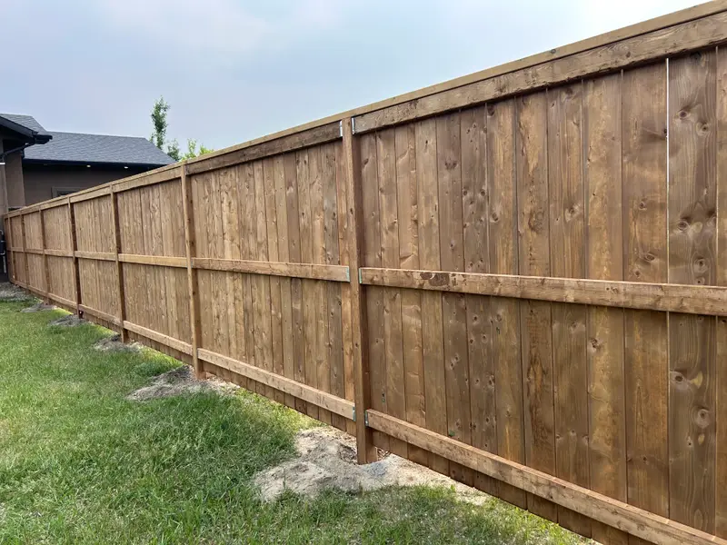 Full-Yard Wood Privacy Fence Long stained wood privacy fence running the full length of a backyard in Saskatoon