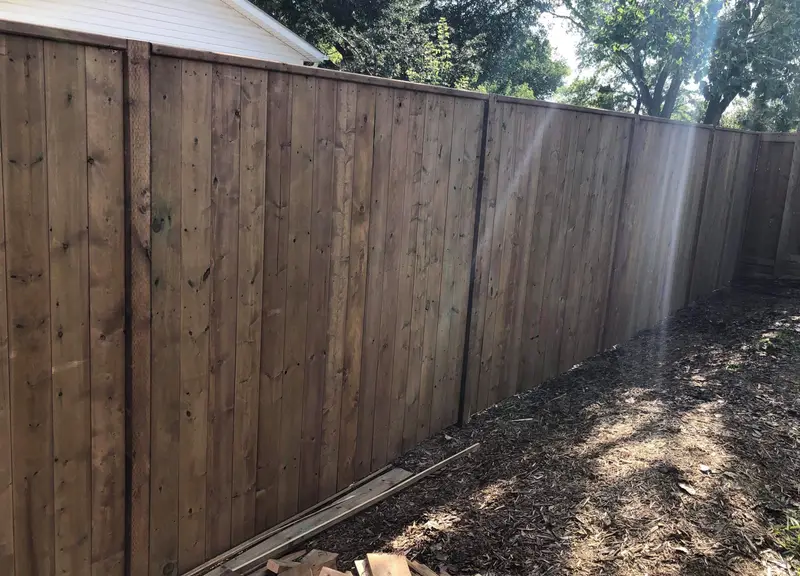 Pressure-Treated Wood Privacy Fence Brown pressure-treated wood privacy fence with vertical boards and a capped top rail in Saskatoon