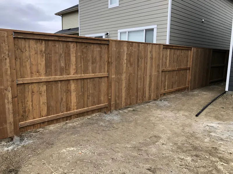 Wood Privacy Fence Installation Newly installed stained wood privacy fence dividing two homes in Saskatoon